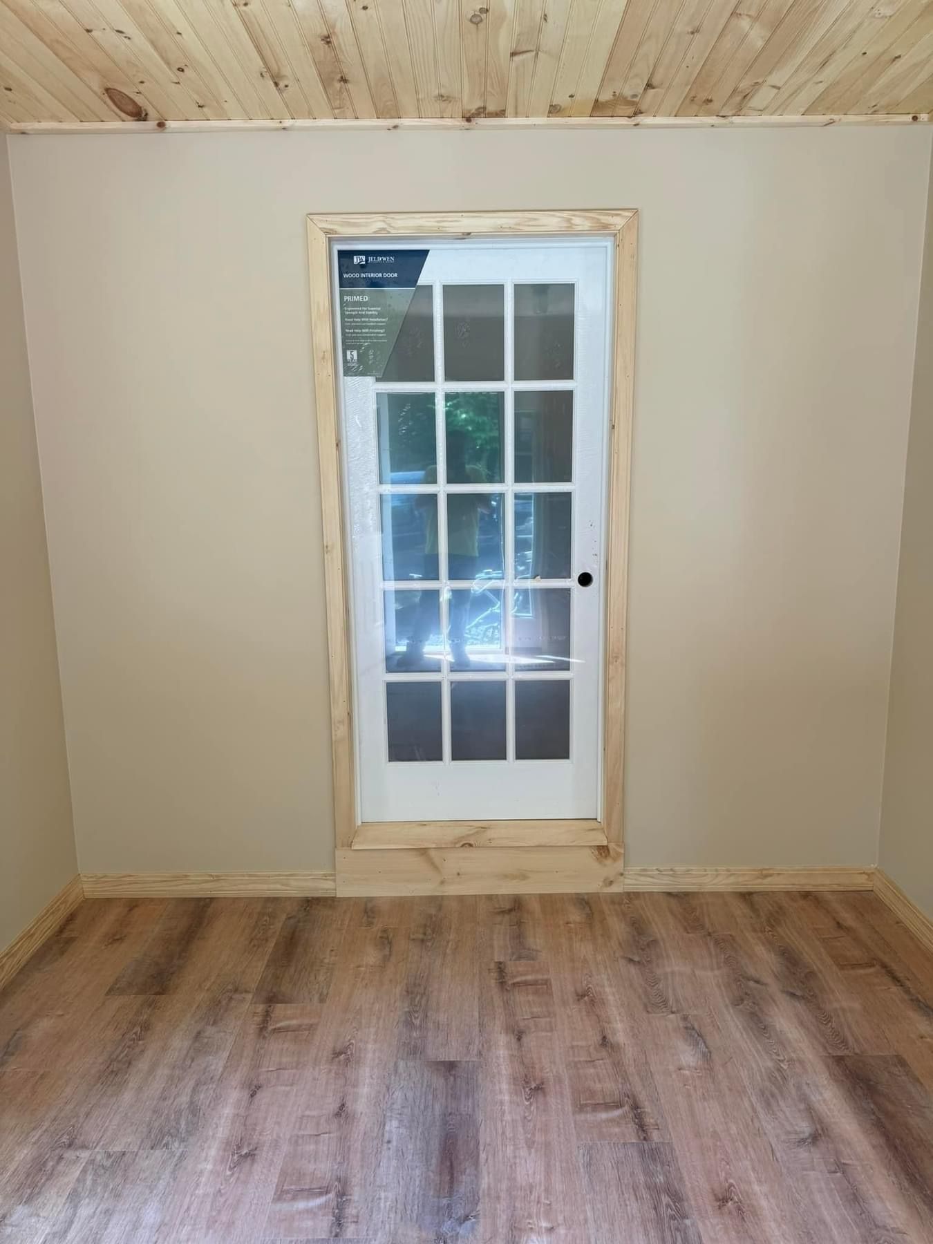 An empty room with hardwood floors and a white door.