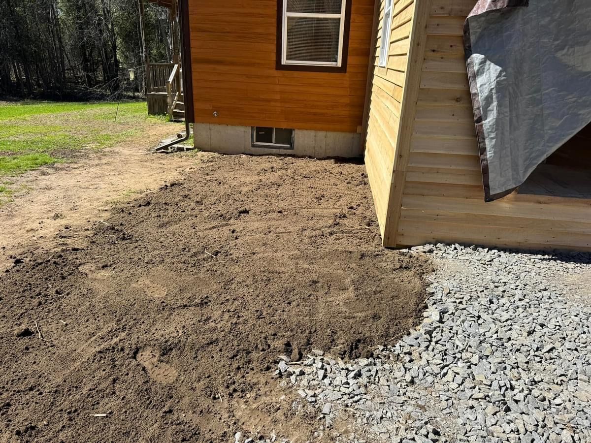 A wooden house is sitting next to a pile of gravel.