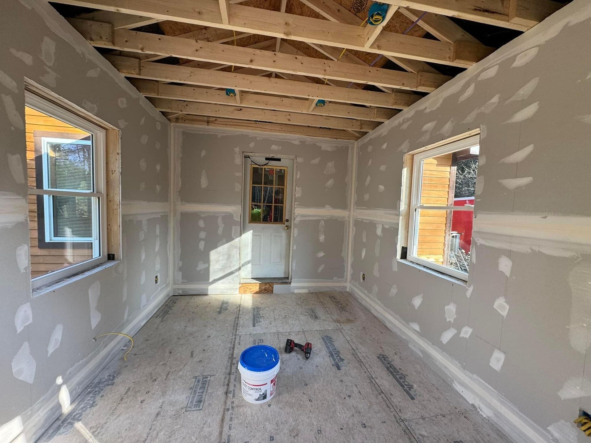 A room under construction with a bucket of paint on the floor.