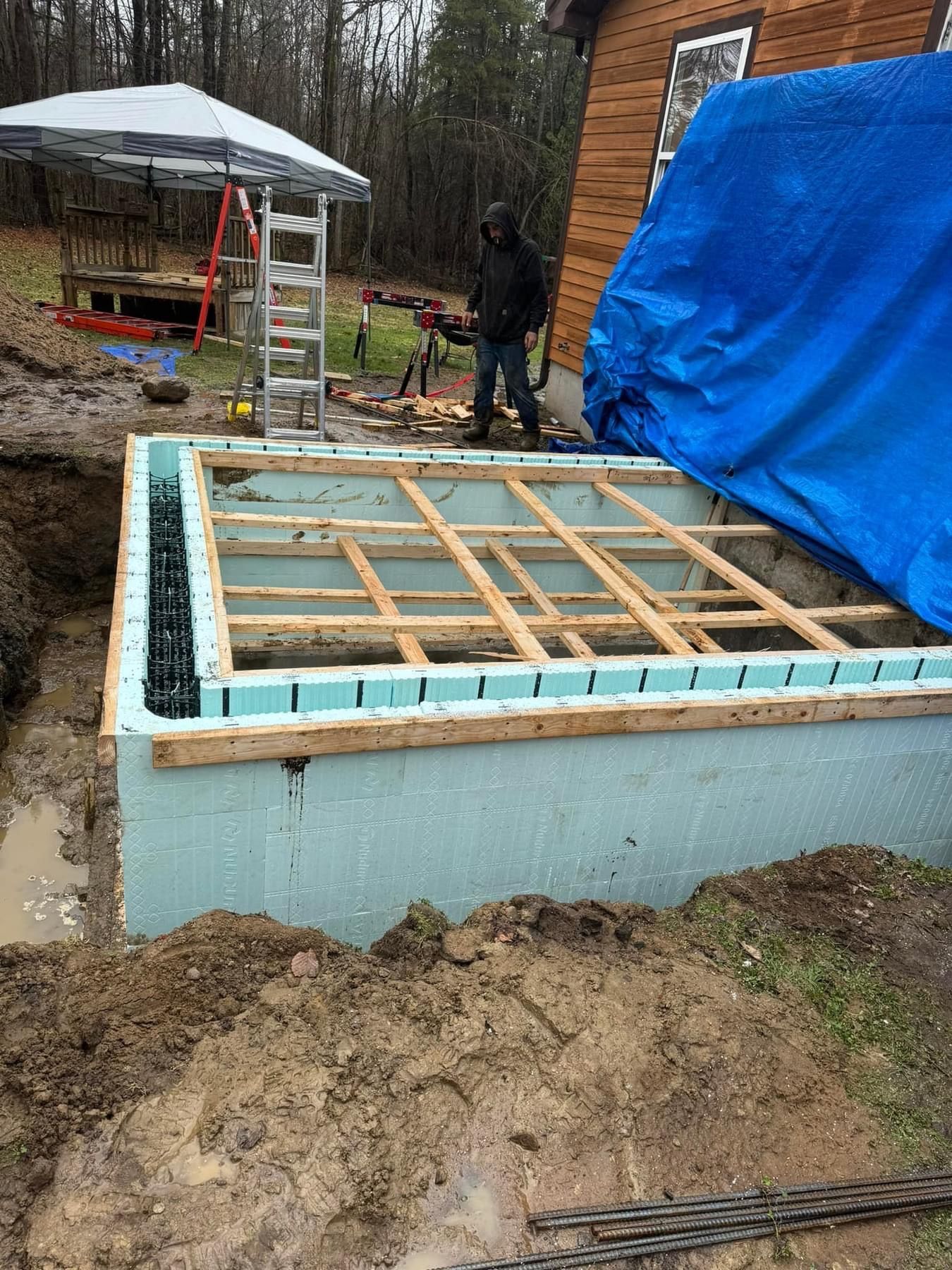 A man is standing next to a blue tarp on a construction site.