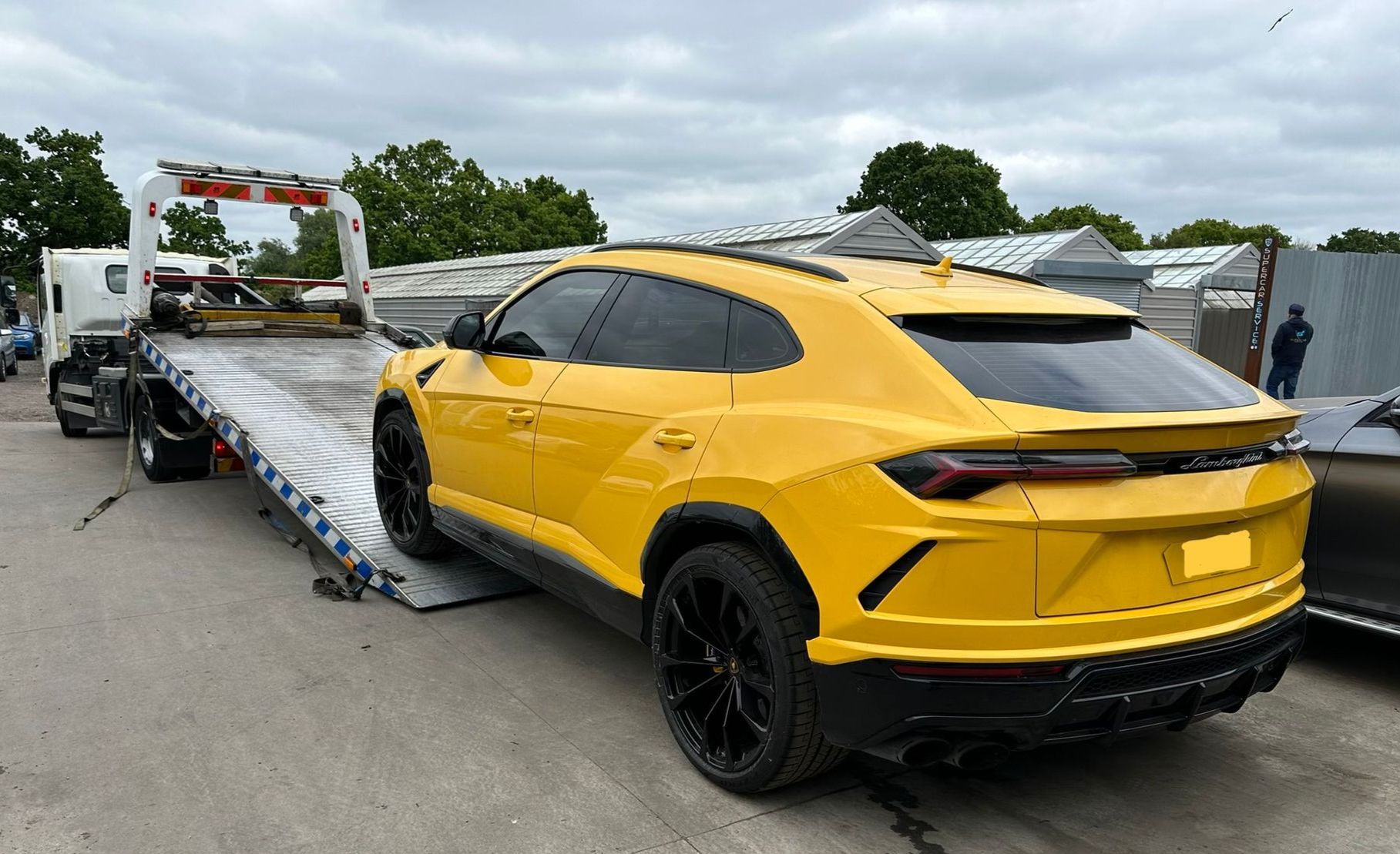 A yellow lamborghini urus is being towed by a tow truck.