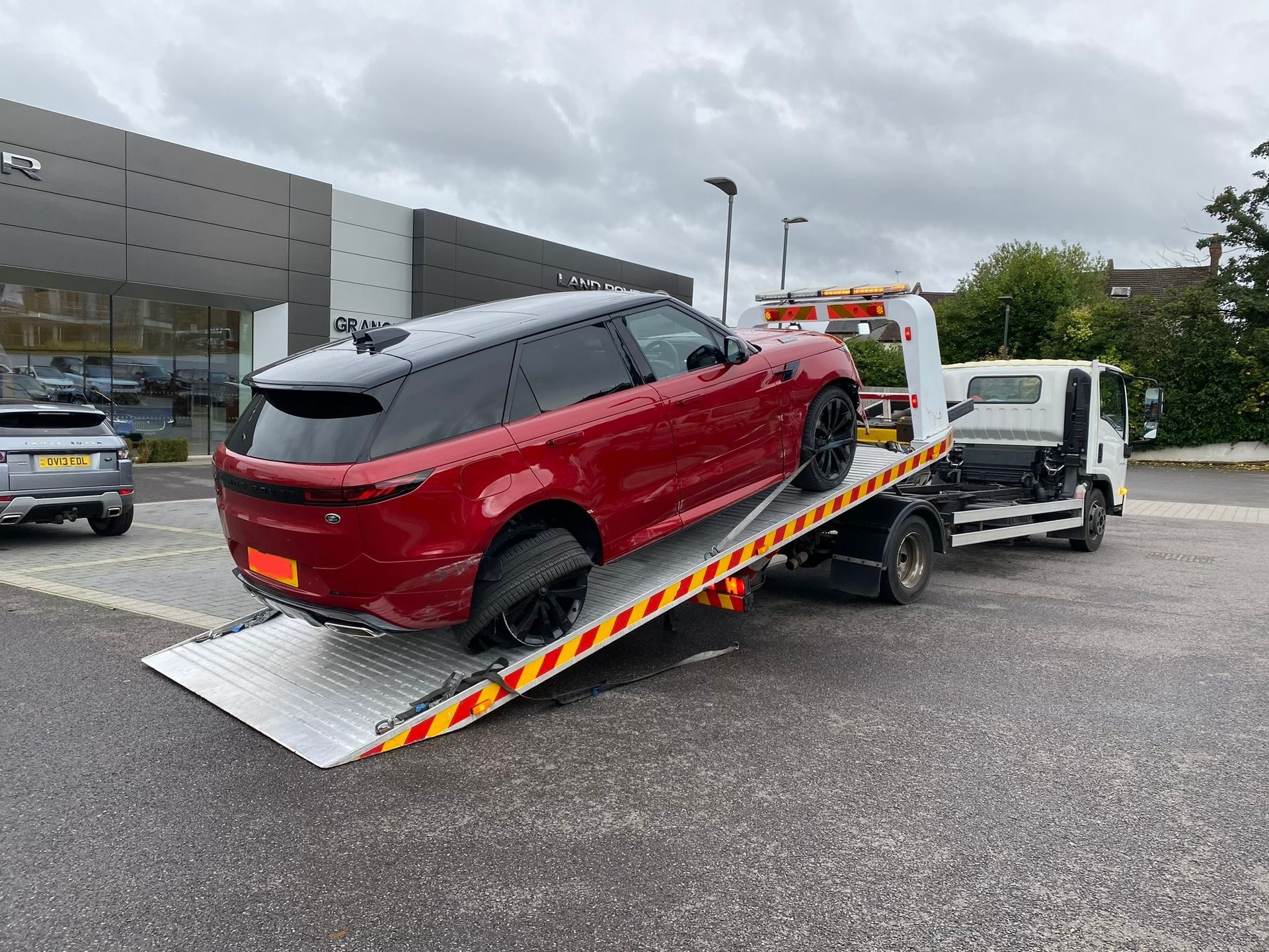 A red range rover is being towed by a tow truck.