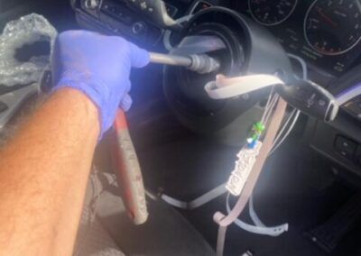 A person wearing blue gloves is working on a car steering wheel