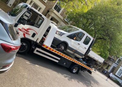 A tow truck is towing a car down a street.