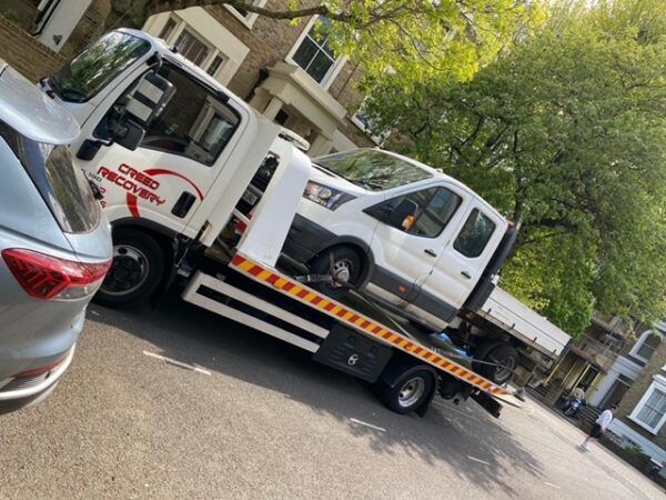 A tow truck is carrying a car on the back of it.