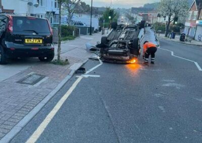A car is on its side on the side of the road.