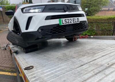A white car is sitting on top of a tow truck.