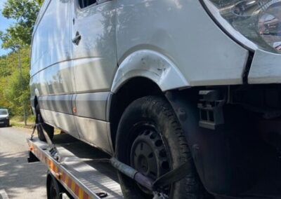 A white van is sitting on top of a tow truck.