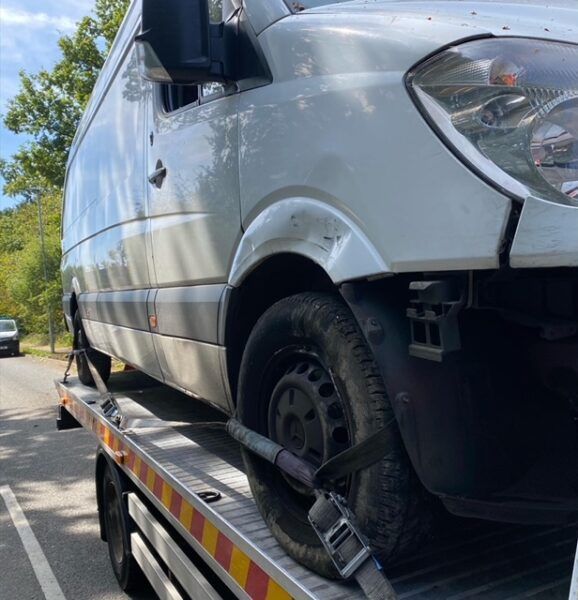 A white van is being towed by a tow truck