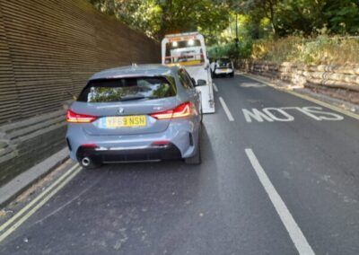 A car is being towed down a road by a tow truck.