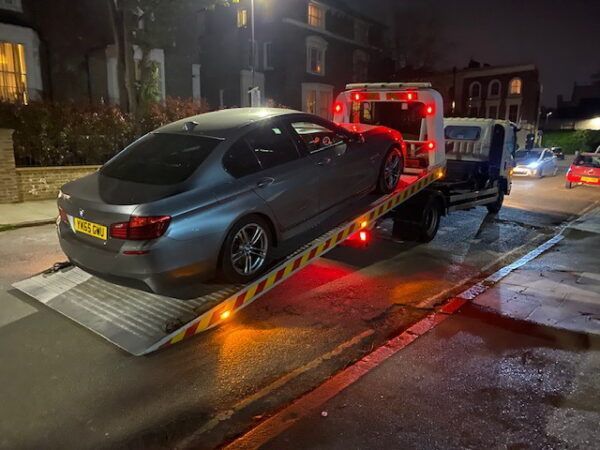A car is being towed by a tow truck on a ramp.