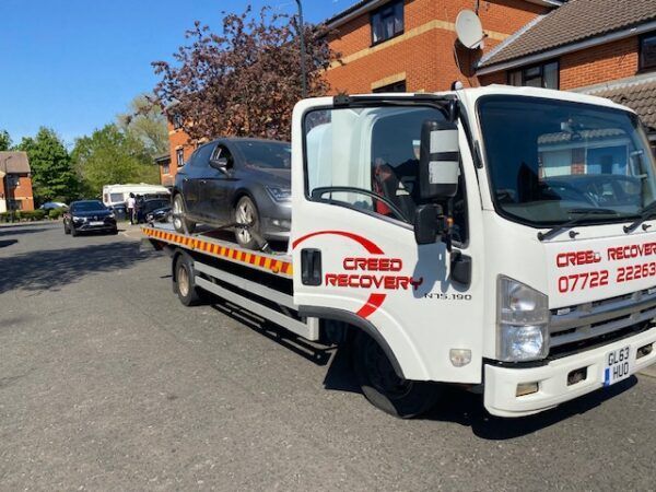 A car is being towed by a creed recovery truck