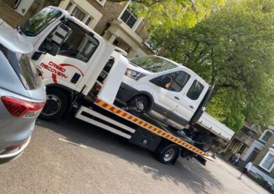 A tow truck is carrying a car on the back of it.