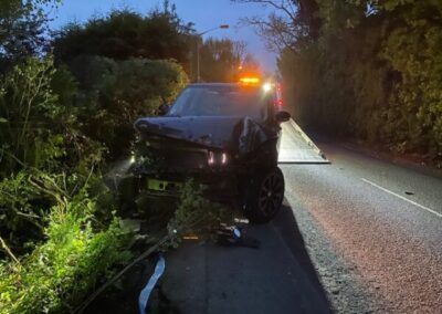 A car has crashed into a bush on the side of the road.