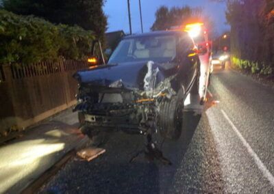 A black car is sitting on the side of the road.
