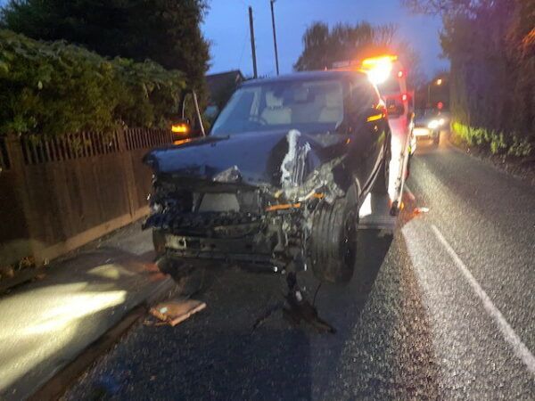 A car that has been damaged in an accident is sitting on the side of the road.