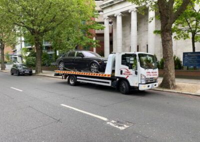 A tow truck is carrying a car on the back of it.