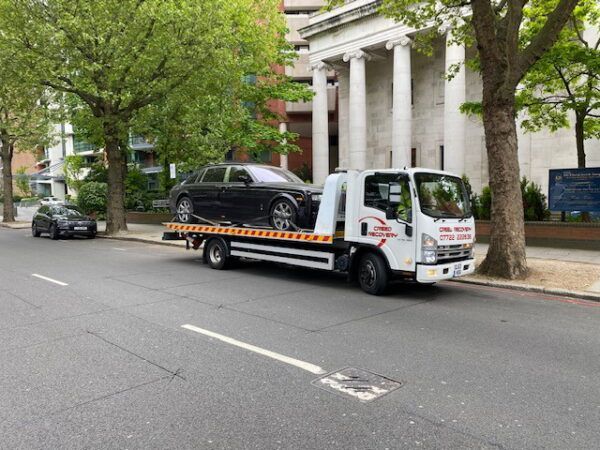 A tow truck is carrying a car on the back of it.