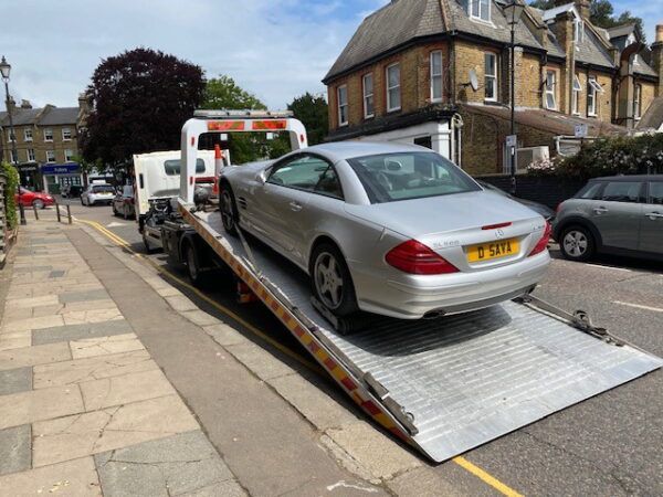 A silver car is being towed by a tow truck