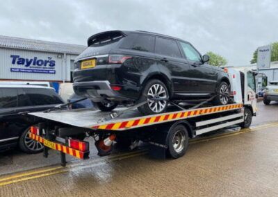 A black range rover is being towed by a tow truck.
