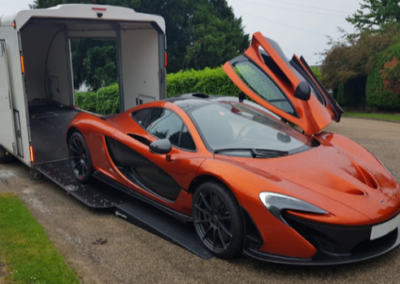 An orange sports car is parked in front of a trailer