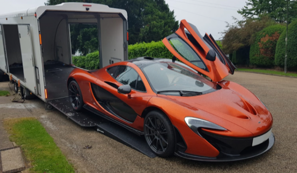 An orange sports car is parked in front of a trailer.