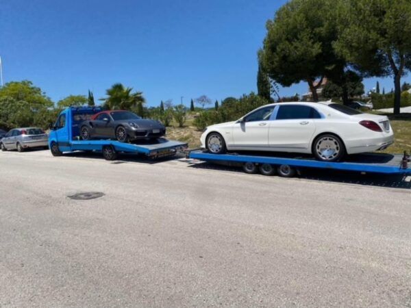 A white car is being towed by a blue tow truck