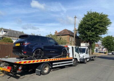 A black range rover is being towed by a tow truck.