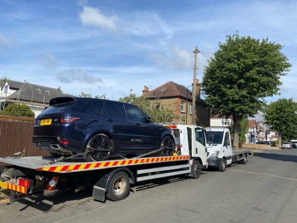 A car is being towed by a tow truck down a street.