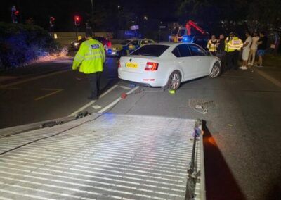 A white car is being towed by a tow truck.