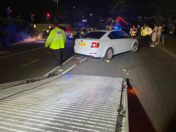 A white car is being towed by a tow truck.