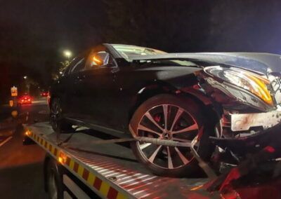 A black car is sitting on top of a tow truck.