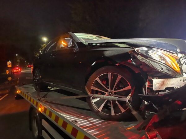 A black car is sitting on top of a tow truck.
