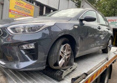 A car with a flat tire is sitting on top of a tow truck.