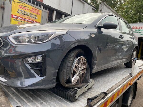 A car with a flat tire is sitting on top of a tow truck.