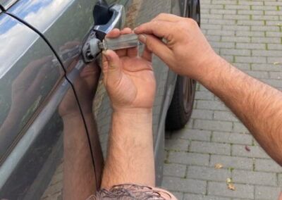 A man is trying to open a car door with a key.