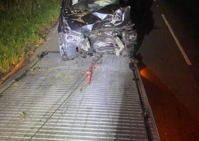 A car is sitting on top of a tow truck on the side of the road.