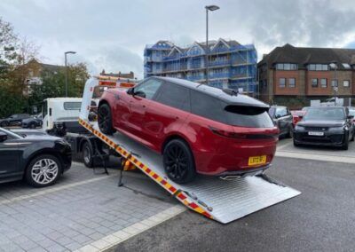 A red car is sitting on top of a ramp in a parking lot.