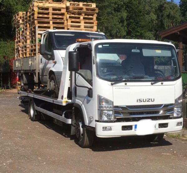 A white isuzu tow truck is parked in a parking lot