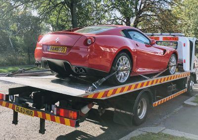 A red sports car is being towed by a tow truck.