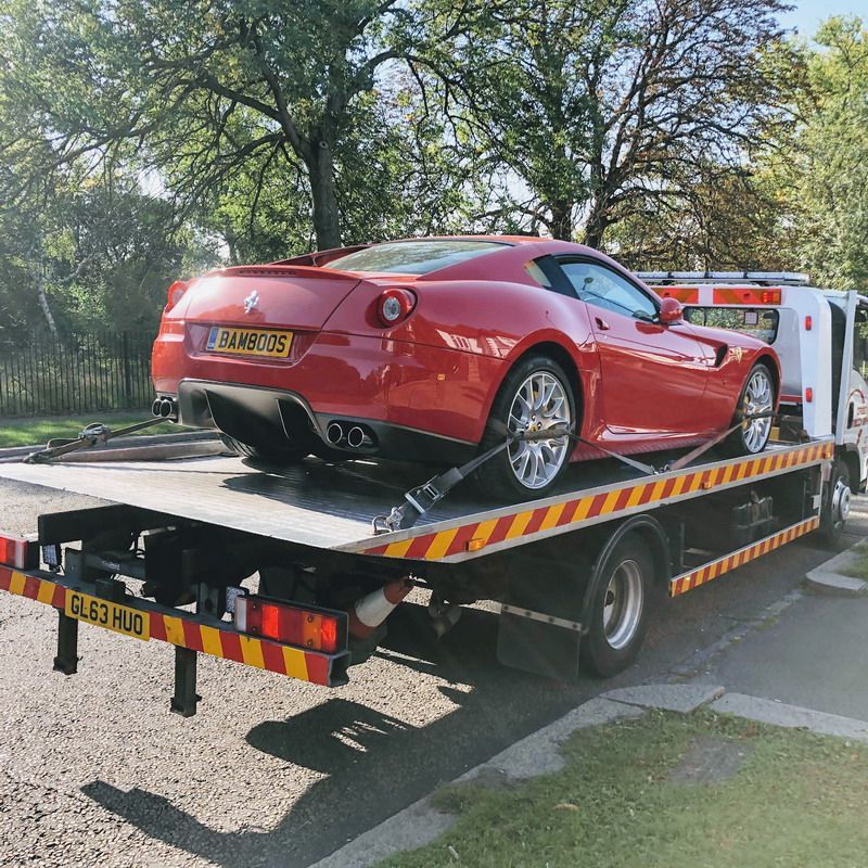 A red sports car is being towed by a tow truck