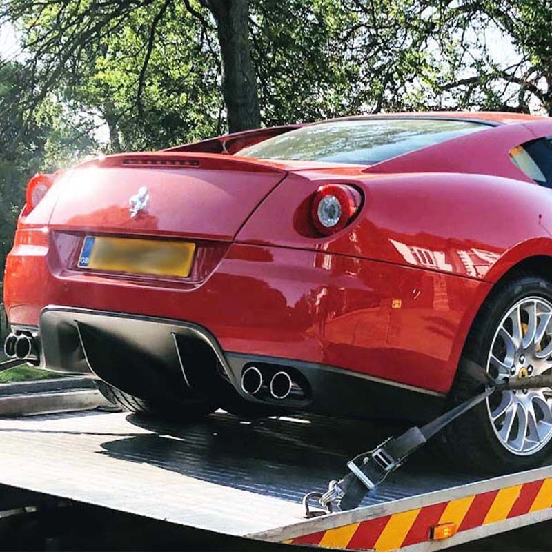 A red sports car is being towed by a tow truck