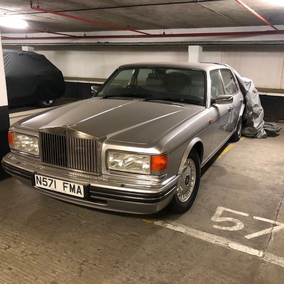 A silver rolls royce parked in a parking garage