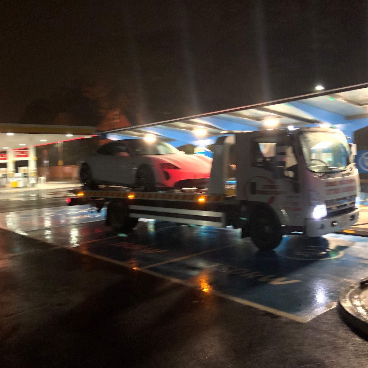 A tow truck is carrying a car in a parking lot