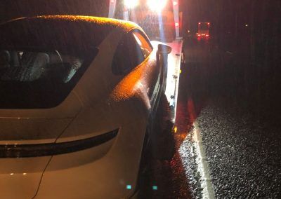 A white car is parked on the side of the road at night.