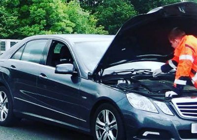 A man is working on a car with the hood open.