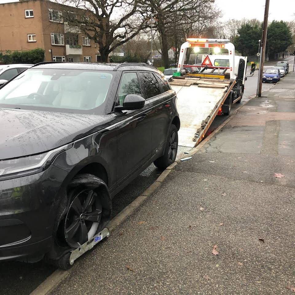A black car is being towed by a tow truck