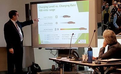 A man is giving a presentation in front of a projector screen.