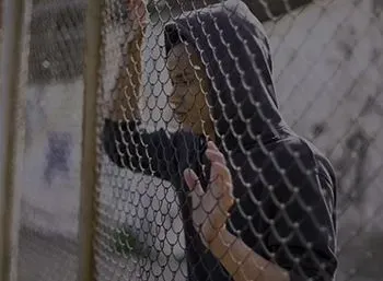 A Man In A Hoodie Is Standing Behind A Chain Link Fence — Pleasanton, CA — Thompson • Garcia Law