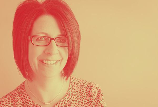 A woman wearing glasses and a leopard print shirt is smiling.